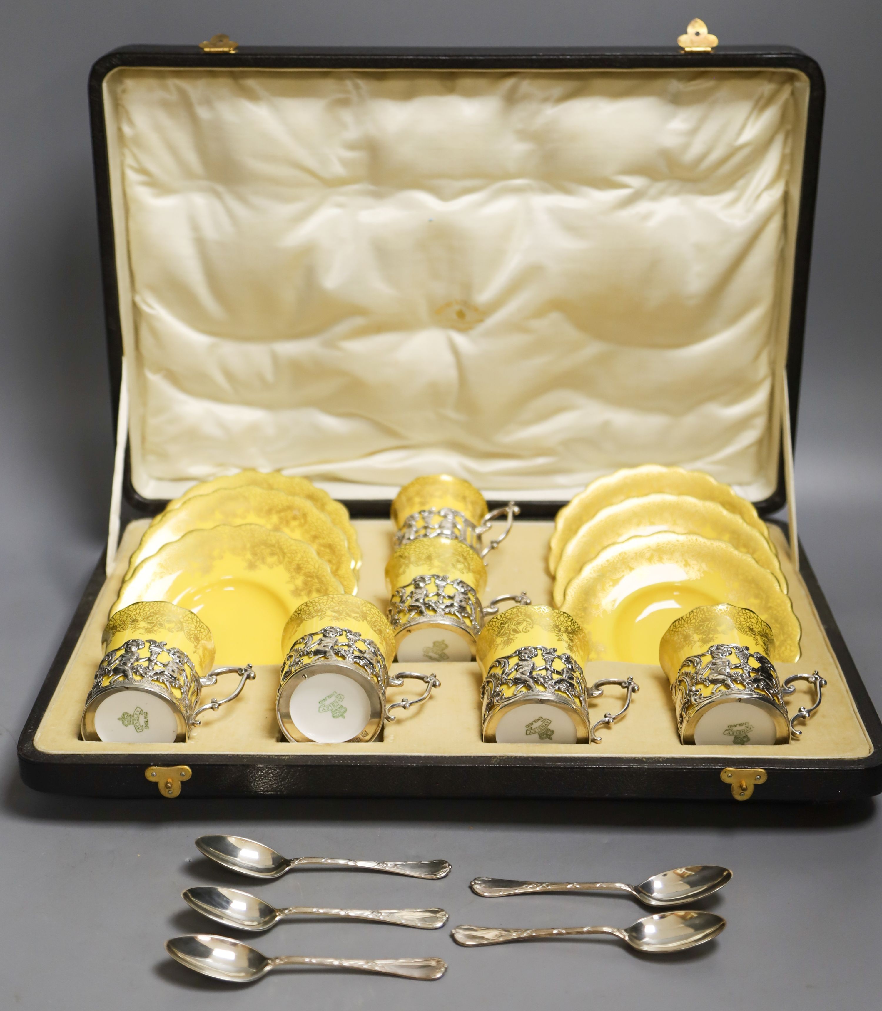 A set of six Aynsley coffee cans and saucers, with silver holders and a set of six silver spoons